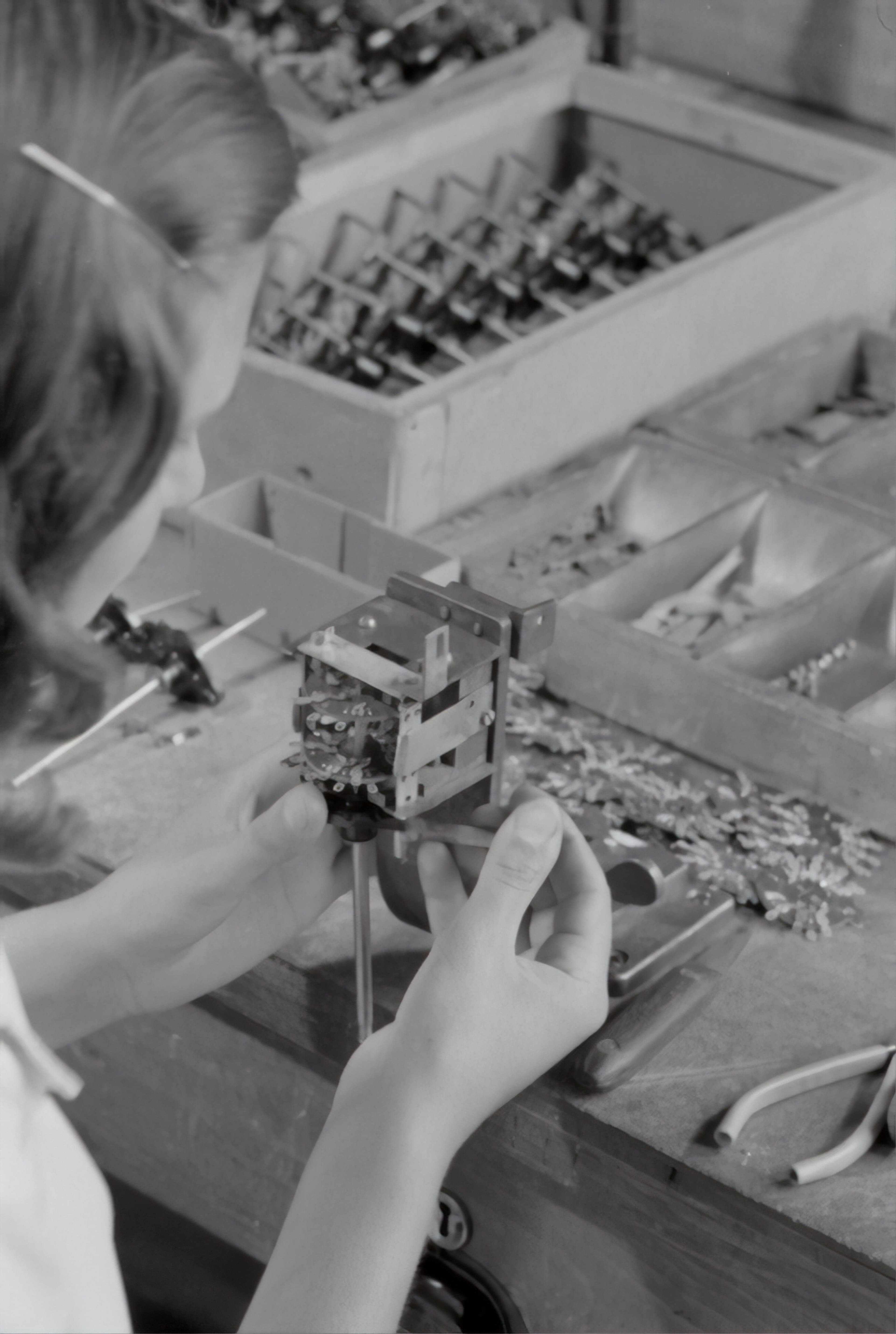 Black-and-white photo of a woman assembling precision components.