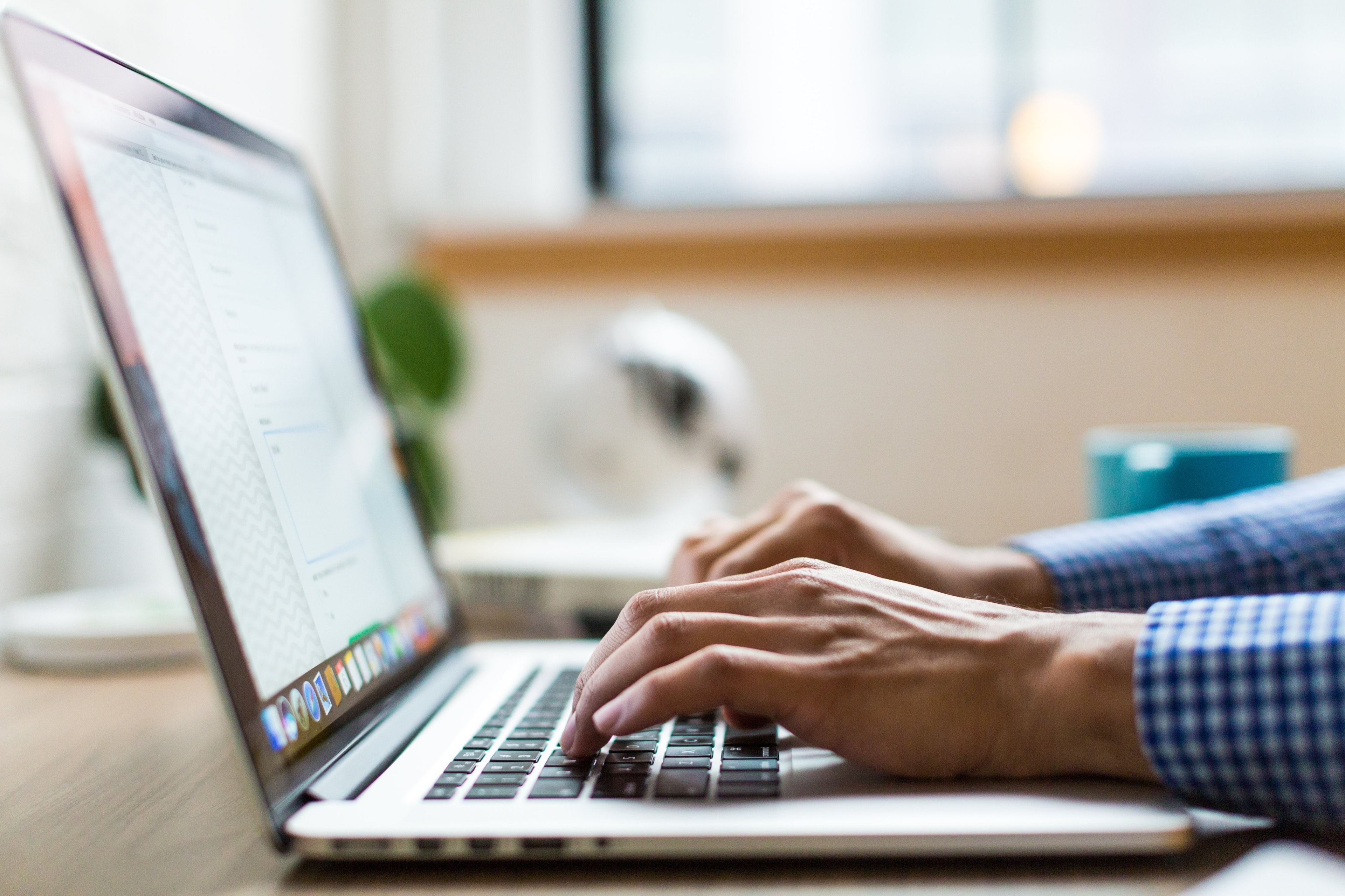 Person typing on a laptop in a modern, well-lit workspace.